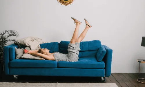 Frau entspannt auf einem blauen Sofa