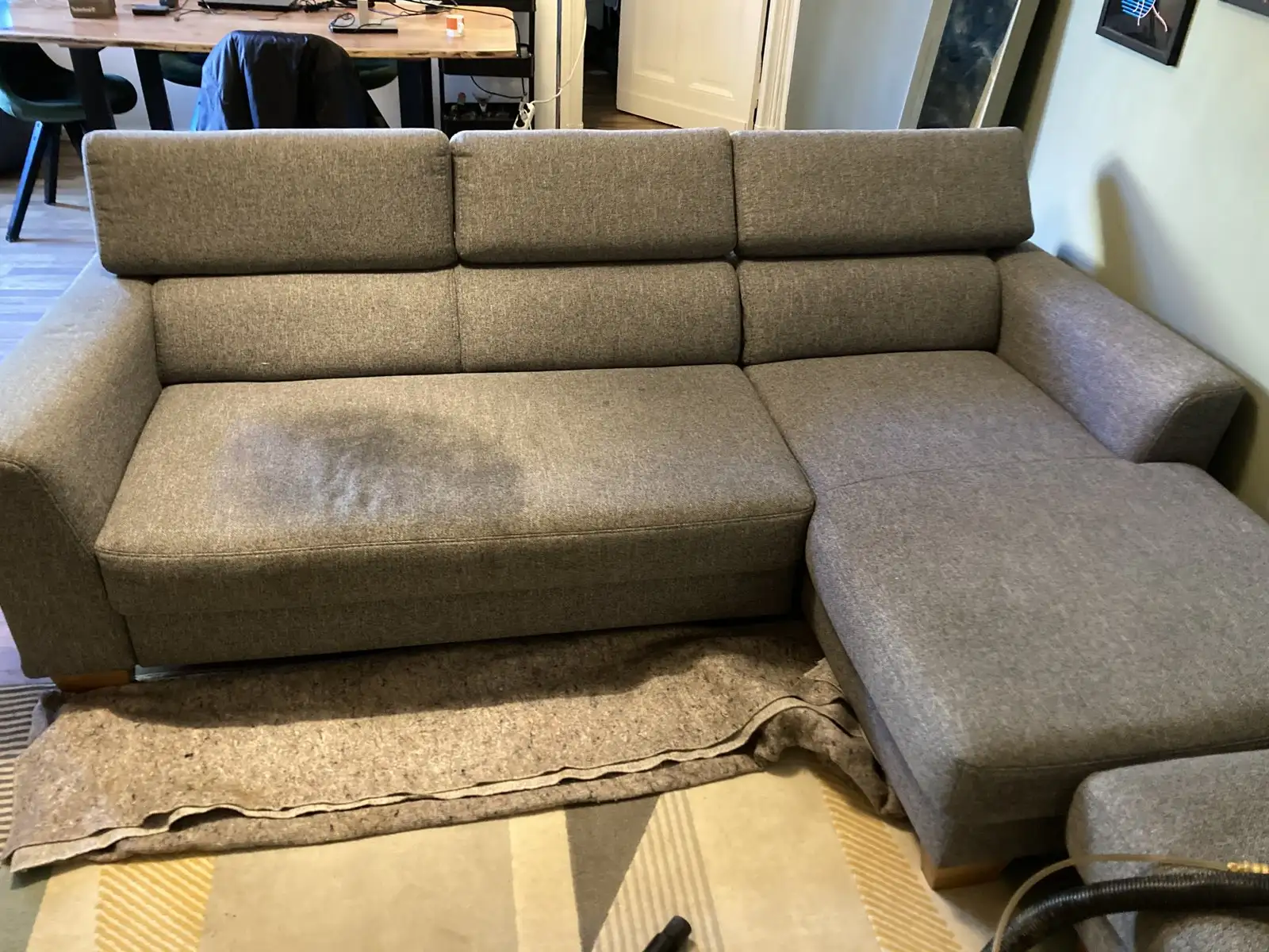 Vorher: graues Ecksofa mit großem Fleck auf der Sitzfläche