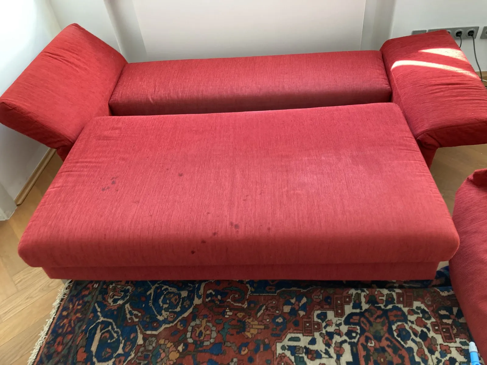 Vorher: rotes Sofa mit Flecken auf der Liegefläche